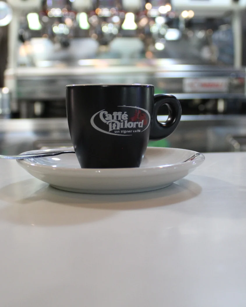 Una tazzina di espresso sul banco del bar de La Vecchia Pesa, con la macchina del caffè sullo sfondo, a Cassino