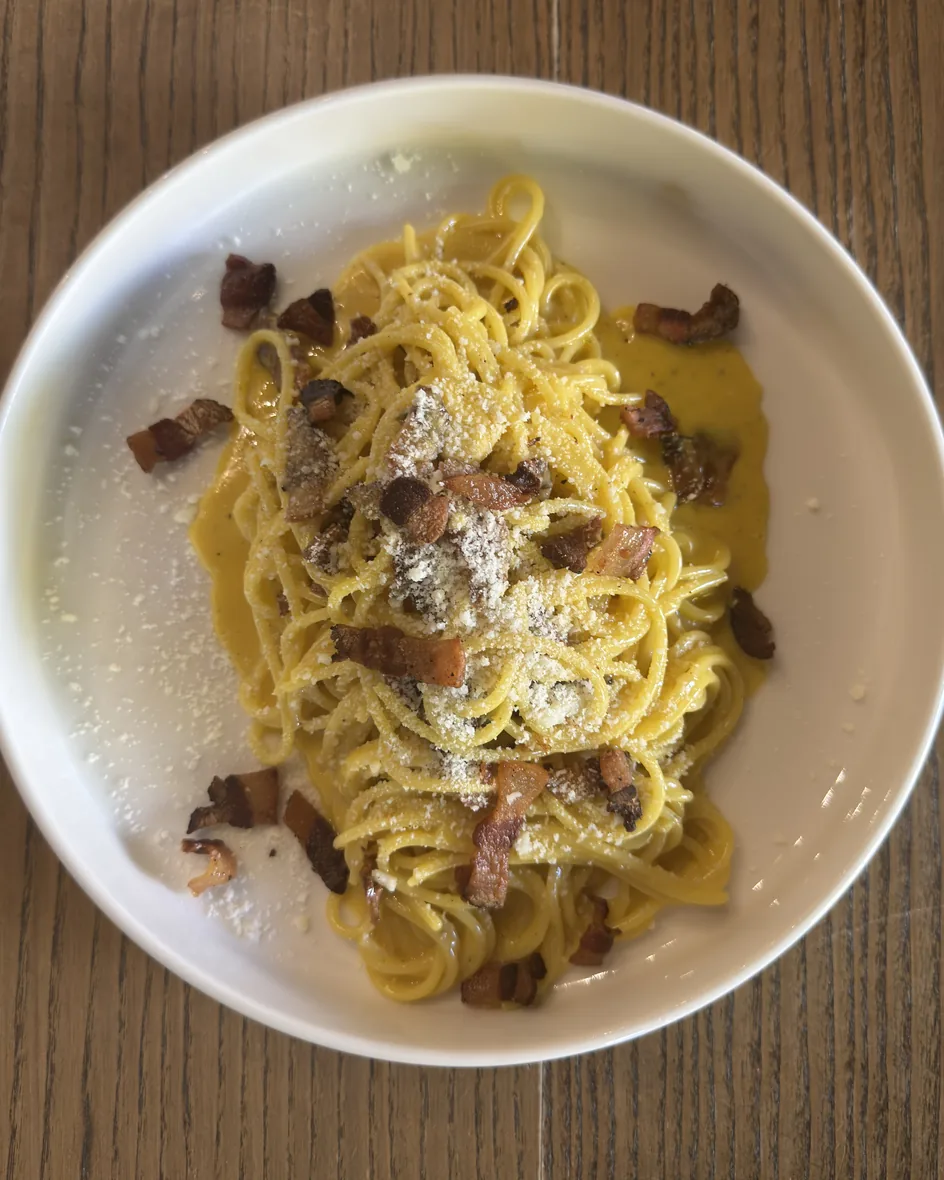 Un piatto di spaghetti alla carbonara con guanciale e pecorino, visto dall'alto sul tavolo del ristorante nel parco