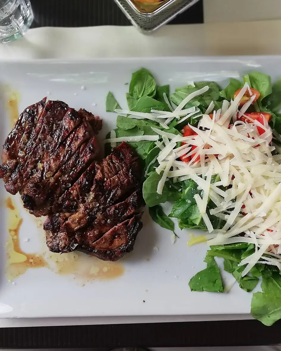 Tagliata servita con rucola, pomodorini e scaglie di grana nel ristorante nel parco