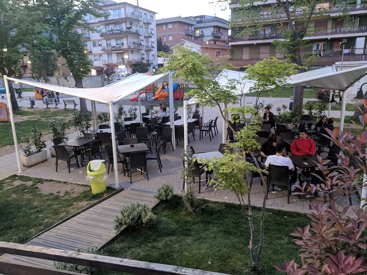 I tavoli all'aperto e il prato al tramonto, con il parco giochi sullo sfondo