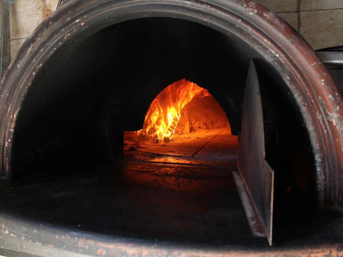Il forno a legna de La Vecchia Pesa acceso, con la fiamma viva in fondo alla cupola