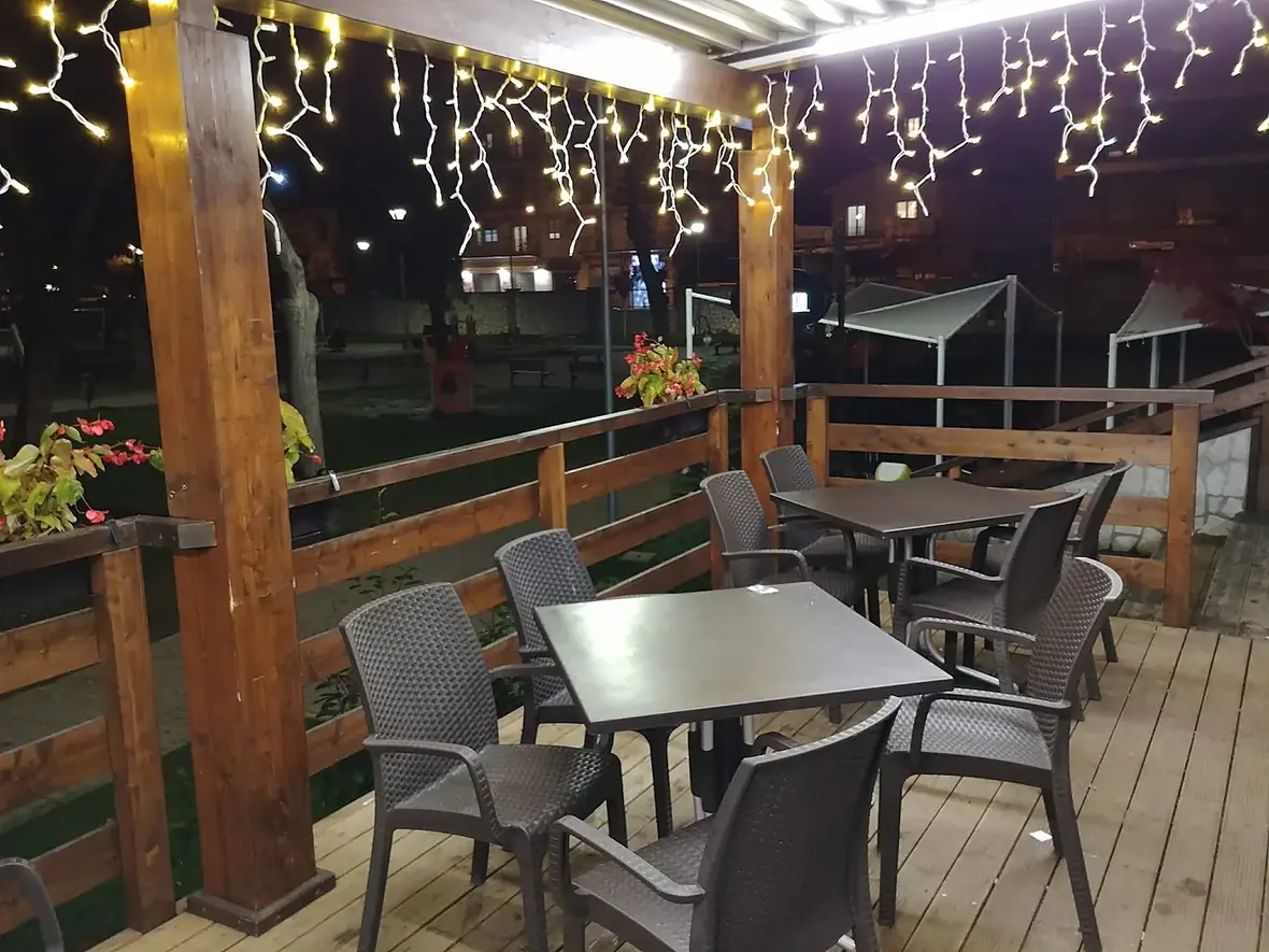 I tavoli all'aperto sotto la tettoia di legno, con le luci accese la sera