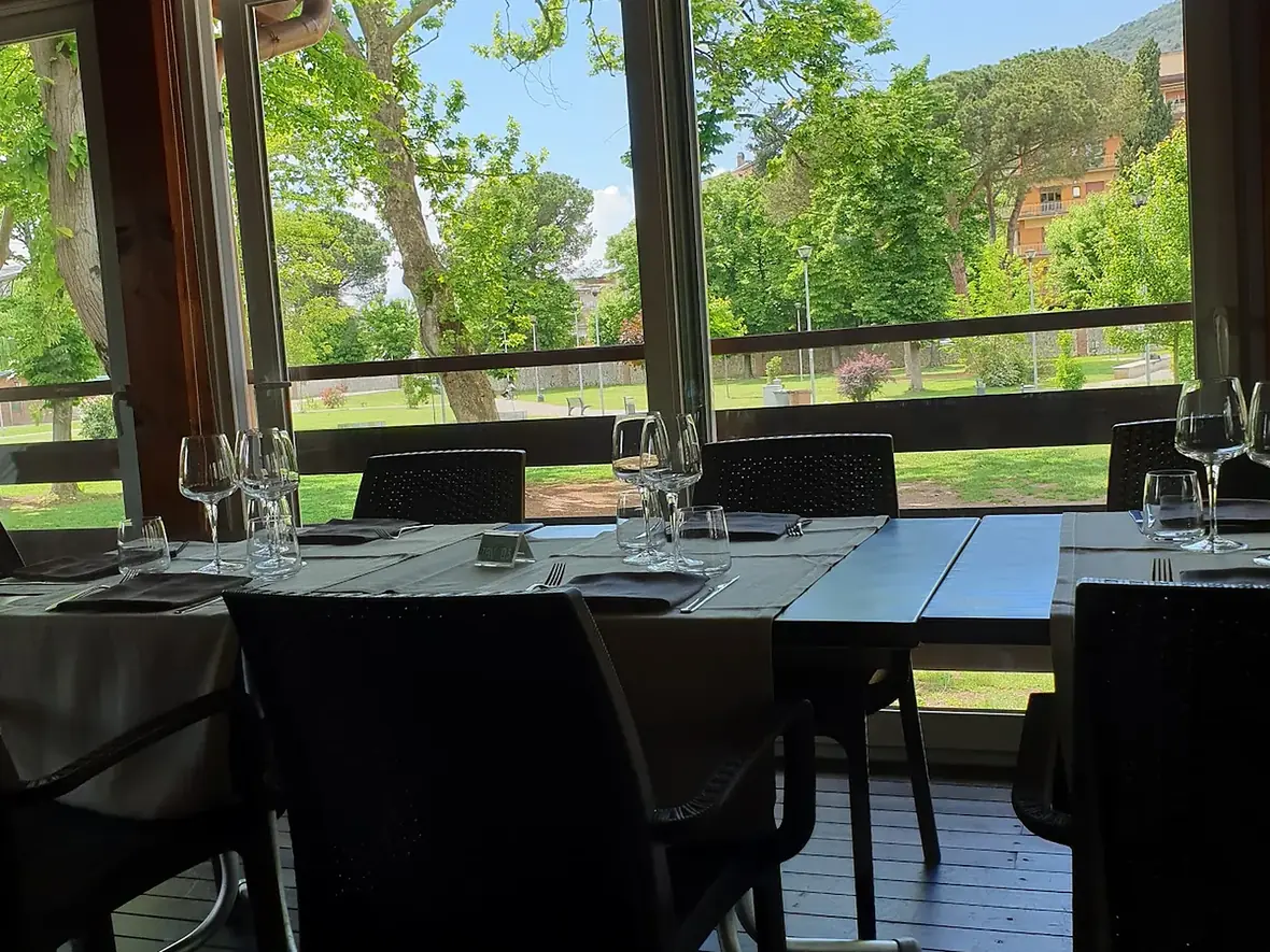 La veranda de La Vecchia Pesa apparecchiata, con le vetrate affacciate sul parco