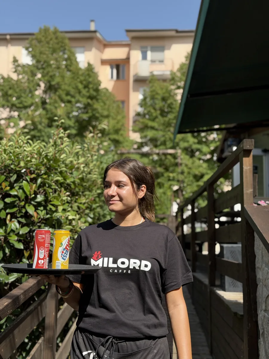 Una cameriera regge il vassoio con le bibite, accanto alla ringhiera del camminamento