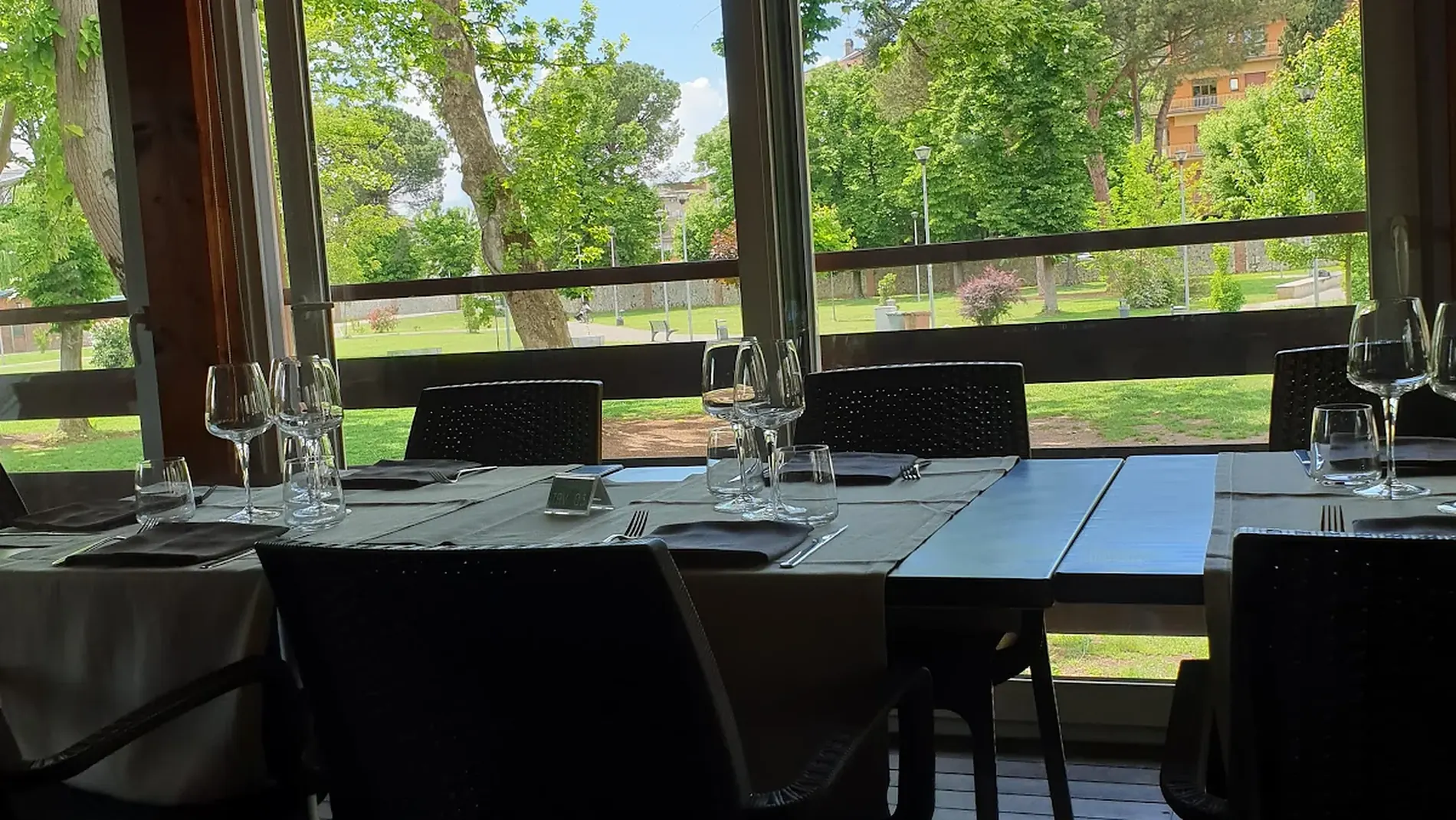 La veranda de La Vecchia Pesa apparecchiata, con le vetrate affacciate sul parco