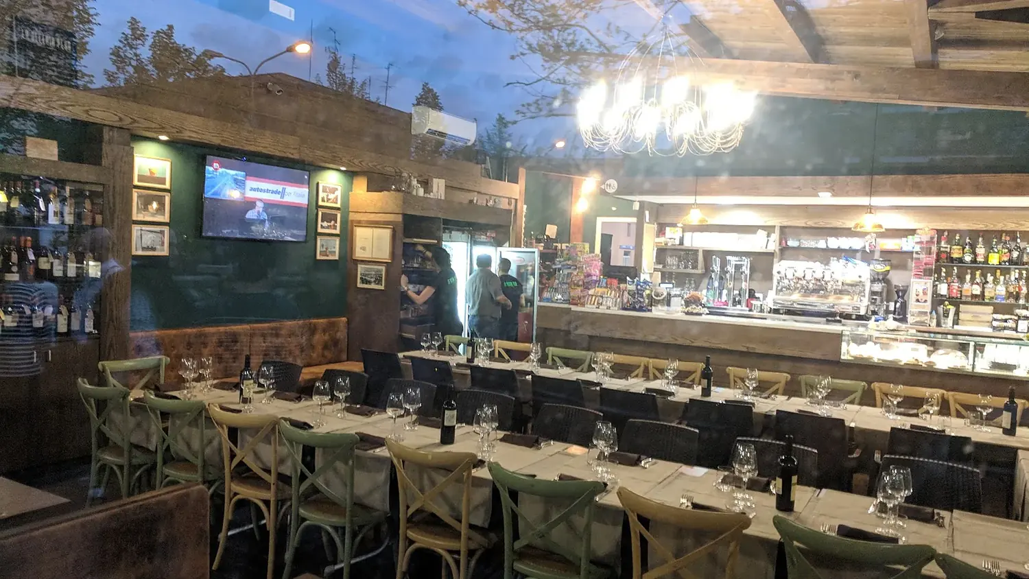 La sala interna con il banco del bar e una lunga tavolata apparecchiata
